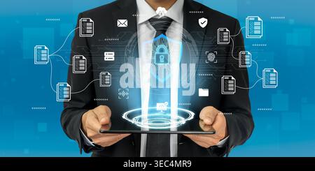 A businessman in a suit holds a tablet while surrounded by digital icons symbolizing data security. This image represents modern technology and secure Stock Photo