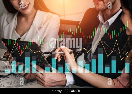 Two professionals in business attire actively engaging in financial analysis while analyzing data visualizations on a tablet in a modern office Stock Photo