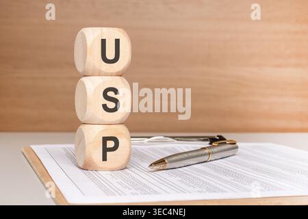 USP (Unique Selling Proposition) text on stacked wooden blocks, resting on business documents with a pen. A powerful concept for marketing strategy, b Stock Photo