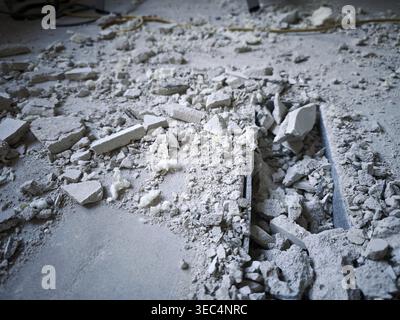 Gray construction debris with broken plaster and concrete rubble on floor. Industrial demolition background Stock Photo