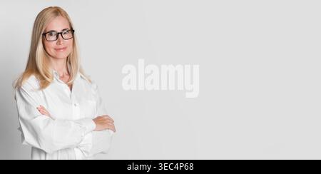 Confident Professional Woman in a White Lab Coat Standing With Arms Crossed Stock Photo