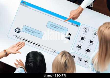 Young professionals discussing digital communication technology with chatbot interface displayed on a large touchscreen device in a modern workspace Stock Photo