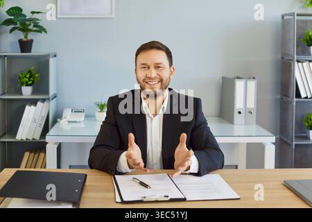 Smiling businessman gesturing to camera during remote office video meeting Stock Photo