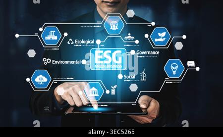 A businessman interacts with a digital tablet showcasing ESG concepts, including environmental, social, and governance factors crucial for sustainable Stock Photo