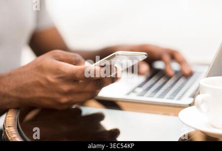 Millennial african american man using cellphone while working Stock Photo
