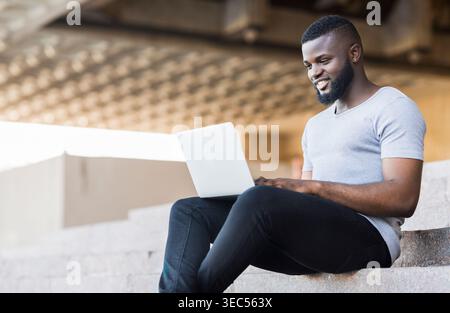 Smiling african american guy coding on his laptop Stock Photo