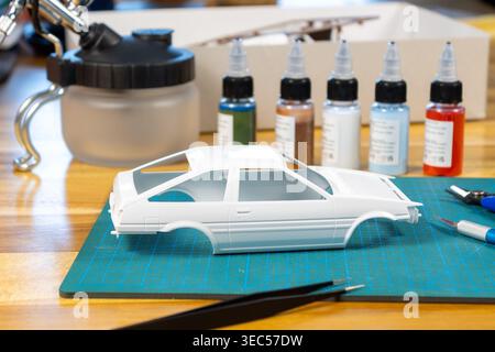 Close-Up of Unpainted Model Car Kit with Tools and Paint on Cutting Mat – Scale Modeling Workspace Stock Photo