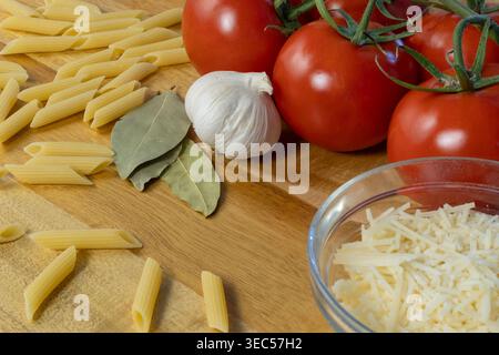 Close-Up of Ripe Tomatoes, Penne Pasta, and Grated Parmesan on Wooden Surface Stock Photo