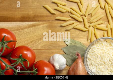 Flat Lay of Ripe Tomatoes, Penne Pasta, and Grated Parmesan on Wooden Surface Stock Photo