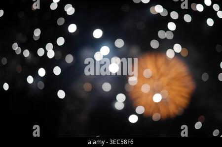 Abstract blurred glowing white and silver bokeh lights from defocused fireworks on dark night sky. Ideal for festive backgrounds celebration overlays Stock Photo