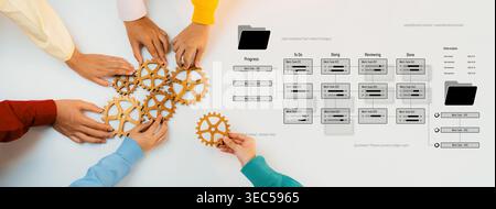 Diverse hands engage collaboratively with gears and workflow documents on a table, symbolizing teamwork, efficiency, and project management in a Stock Photo