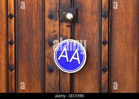 An Alcoholics Anonymous meeting sign hanging on a door knob of a fancy wooden door. Stock Photo