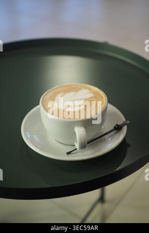 Coffee cup on a green tray in a cafe setting Stock Photo