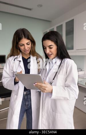 Female doctor guides colleague, working, preparing medical report together Stock Photo