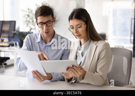 Team collaborating on project details using tablet and printed documents Stock Photo