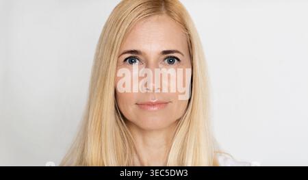 Portrait of a Woman With Long Blonde Hair and Striking Blue Eyes Against a Neutral Background Stock Photo