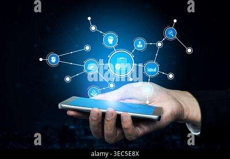 A close-up of a hand holding a smartphone with glowing digital icons and network lines, symbolizing modern technology, data management, and Stock Photo