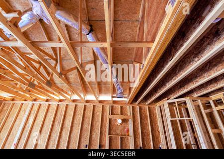 Wooden beams, ductwork are part of construction of new house ongoing building work inside. Stock Photo