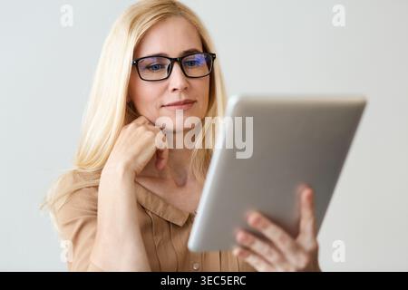 Female Financier Reading News On Tablet Online Stock Photo