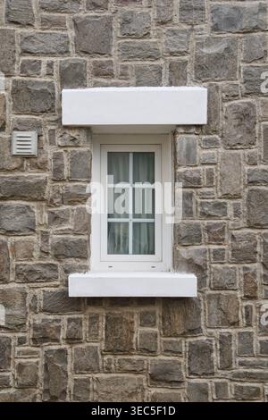 white framed window with internal muntins in stone wall, rectangular window with curtains and sill, front view full frame texture Stock Photo