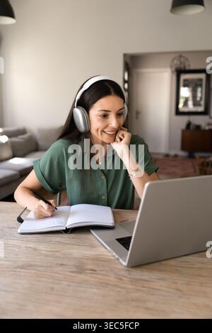 Adult woman taking notes during online meeting Stock Photo