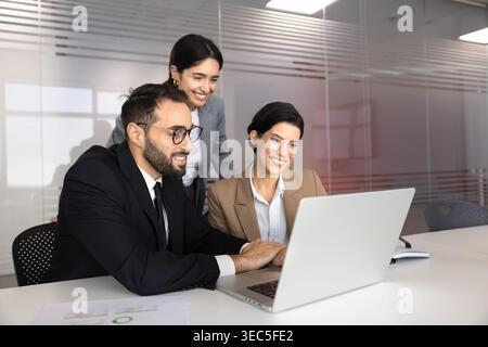 Diverse colleagues reviewing information on laptop at office desk Stock Photo