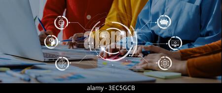 Dynamic team collaborating on innovative strategies using technology. Diverse hands engage with laptops and digital icons, enhancing productivity in a Stock Photo