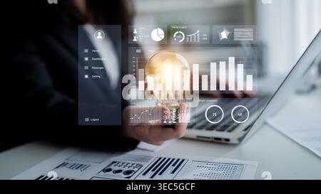 A business professional engages with innovative data analysis in a modern office, holding a light bulb while exploring insights through a digital Stock Photo