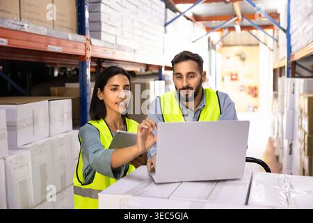 Logistics workers using laptop for inventory management Stock Photo