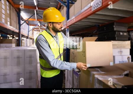 Worker in uniform organizing boxes on shelves in warehouse Stock Photo