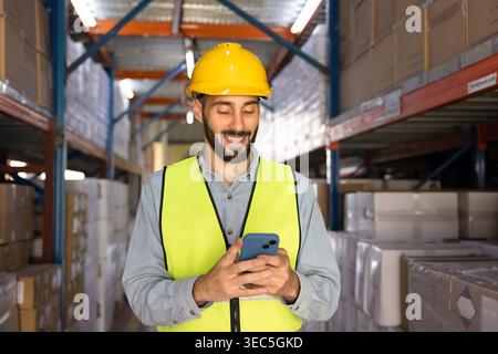 Warehouse worker using smartphone in logistics facility Stock Photo