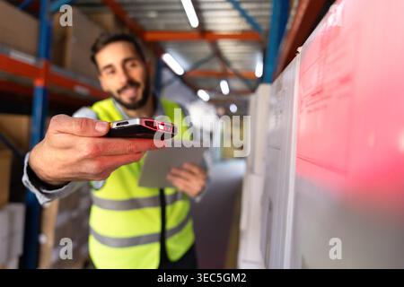 Worker scanning barcode on package with scanner in warehouse aisle Stock Photo