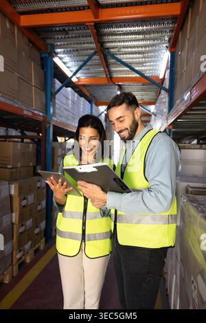Warehouse workers reviewing inventory data on digital tablet and clipboard Stock Photo
