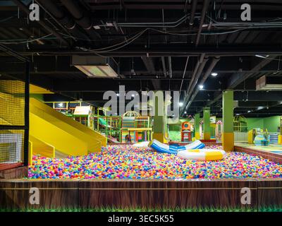 A vibrant indoor playground featuring a large multi-colored ball pit, yellow slides, and various play structures designed for children's recreation an Stock Photo