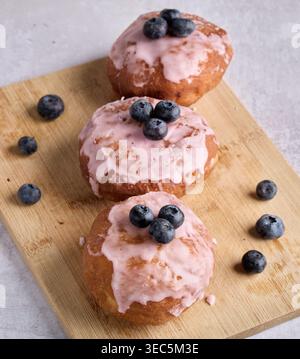 Pink Glazed Donuts with Fresh Blueberries on Board Stock Photo