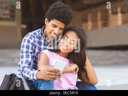 Young Couple Enjoying Time Together While Looking at a Smartphone Outdoors Stock Photo
