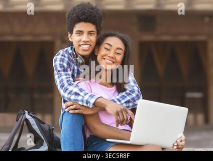 Young Couple Enjoys Studying Together Outdoors on a Sunny Day With a Laptop in Hand Stock Photo