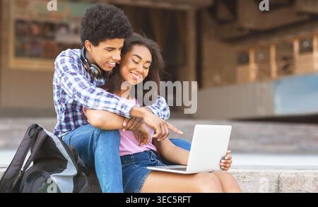 Young Couple Enjoying a Casual Moment Together While Working on a Laptop Outside Stock Photo