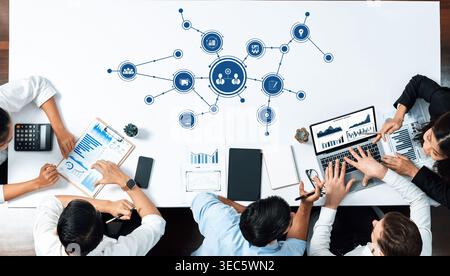 A dynamic business meeting featuring diverse professionals engaged in analyzing charts and data. The setting emphasizes teamwork and digital Stock Photo