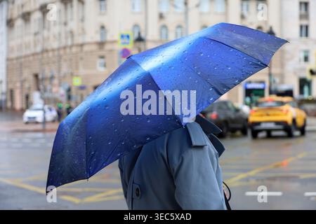 Rain in city, woman with blue umbrella standing on a street on cars background Stock Photo