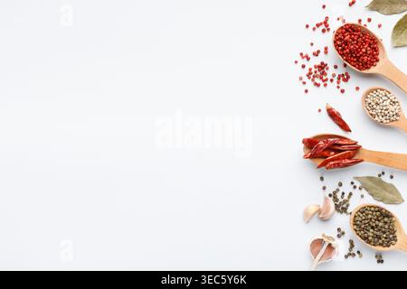 Various peppercorns in spoons on white background Stock Photo