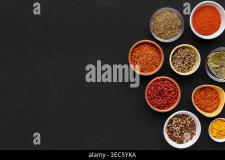 Assortment of spices in bowls on black background Stock Photo