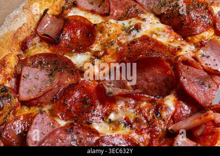 Close up of a freshly baked pizza with delicious toppings, cheese, pepperoni, ham, pineapple and other ingredients. Stock Photo