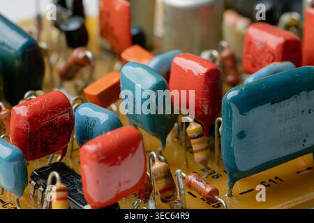 Close-up of a vintage circuit board with various colorful resistors and capacitors. Retro electronic hardware architecture. Detailed internal view of Stock Photo