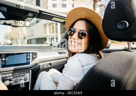 Young woman smiling inside convertible car during city travel Stock Photo