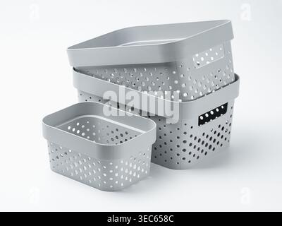 Stack of grey plastic storage baskets with hole pattern on white background. Minimalist home organization and decluttering concept. Studio shot of lau Stock Photo