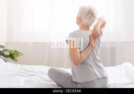 Elderly woman touching her hands behind her back Stock Photo
