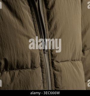 Close-up of a high-quality metal YKK zipper on a brown olive textile jacket. Detailed view of the slider and teeth Stock Photo