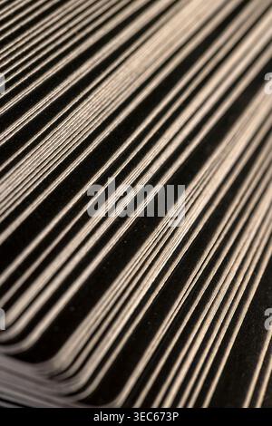 Cards in a stack, black playing cards with a matte surface and light ends on a dark background with clear details of the paper texture and lines close Stock Photo