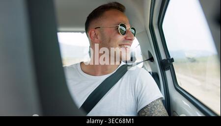 Man, thinking and road trip in car window with smile, travel vacation or sunglasses for weekend break. Happy, person and journey in vehicle with Stock Photo